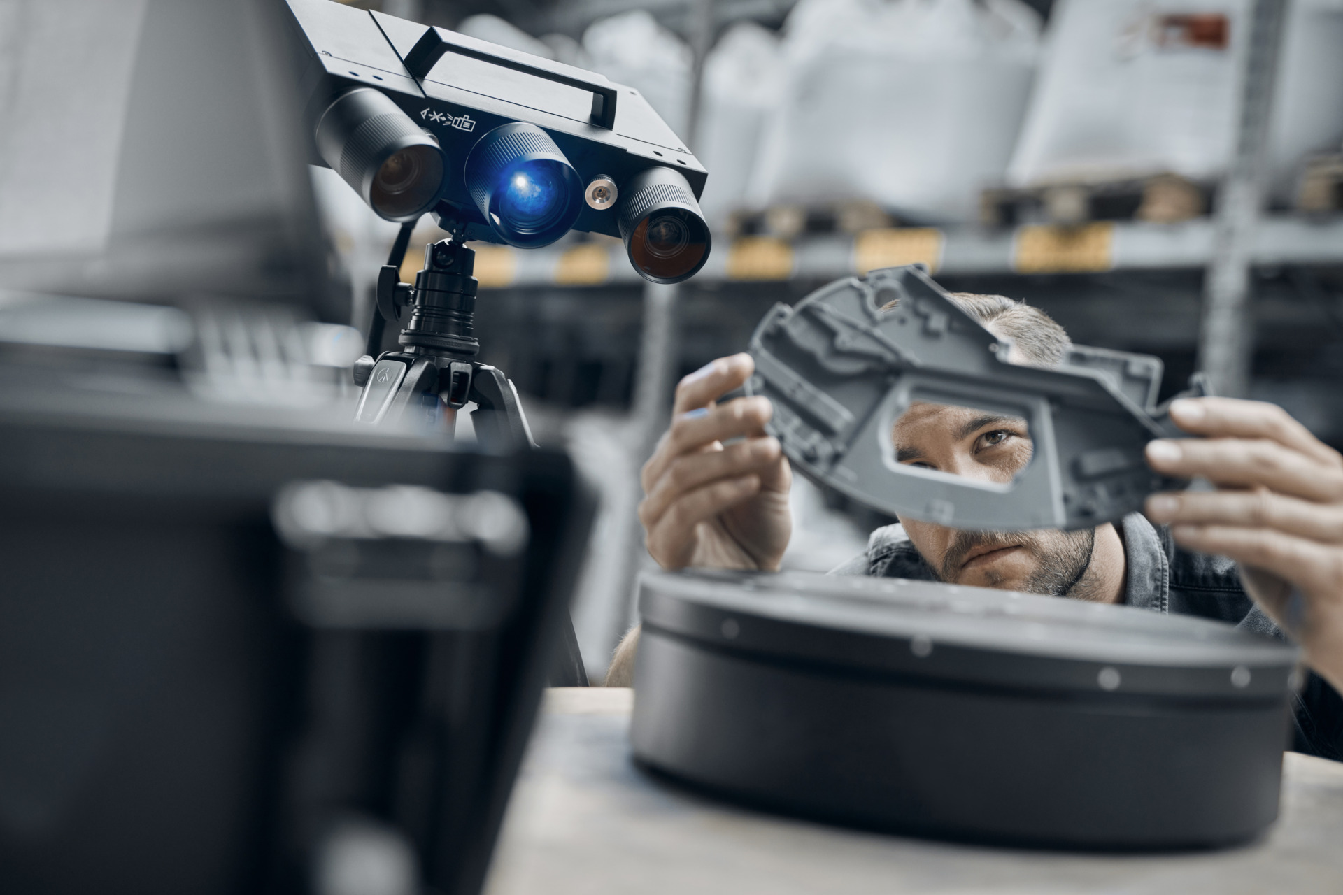 atos-q_3d-scanning_zeiss-multimedia-part A person inspecting a grey plastic part using a 3D scanner and a rotation table.