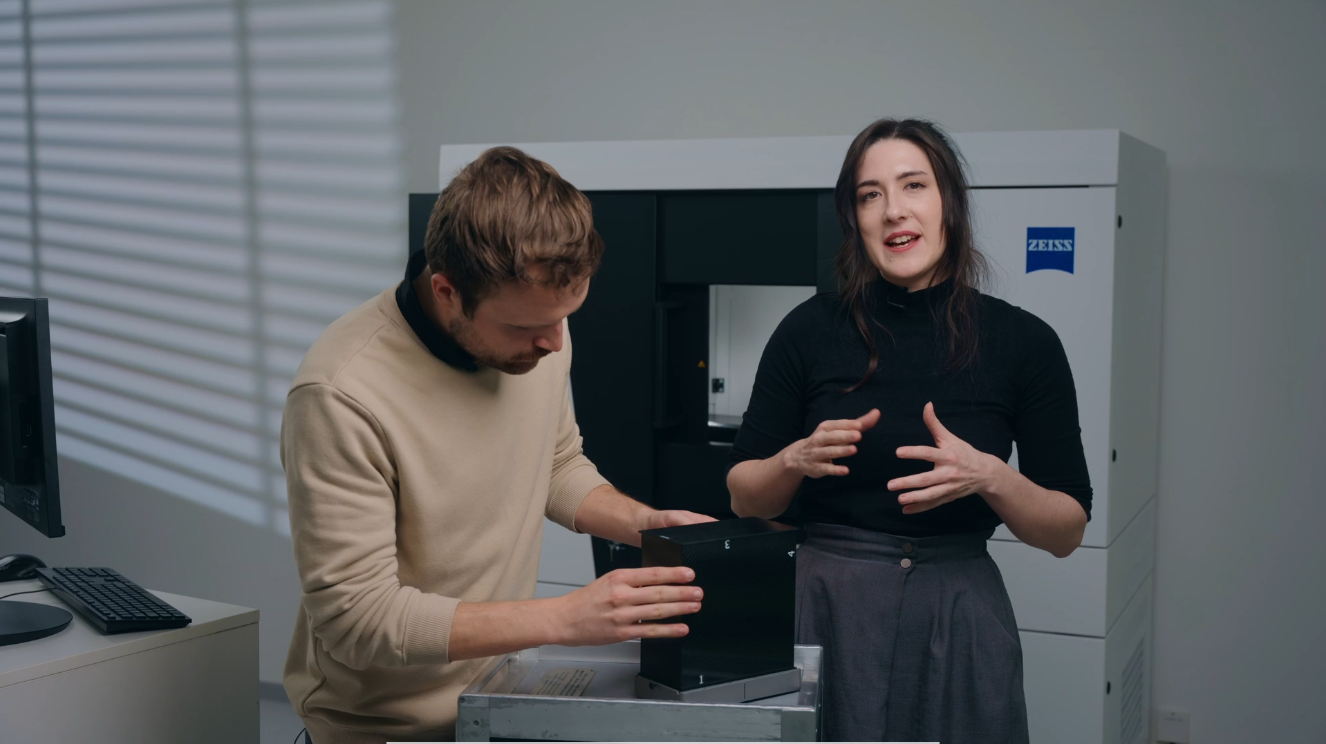 A man and a woman talking about a calibration panel infront of a CT scanner
