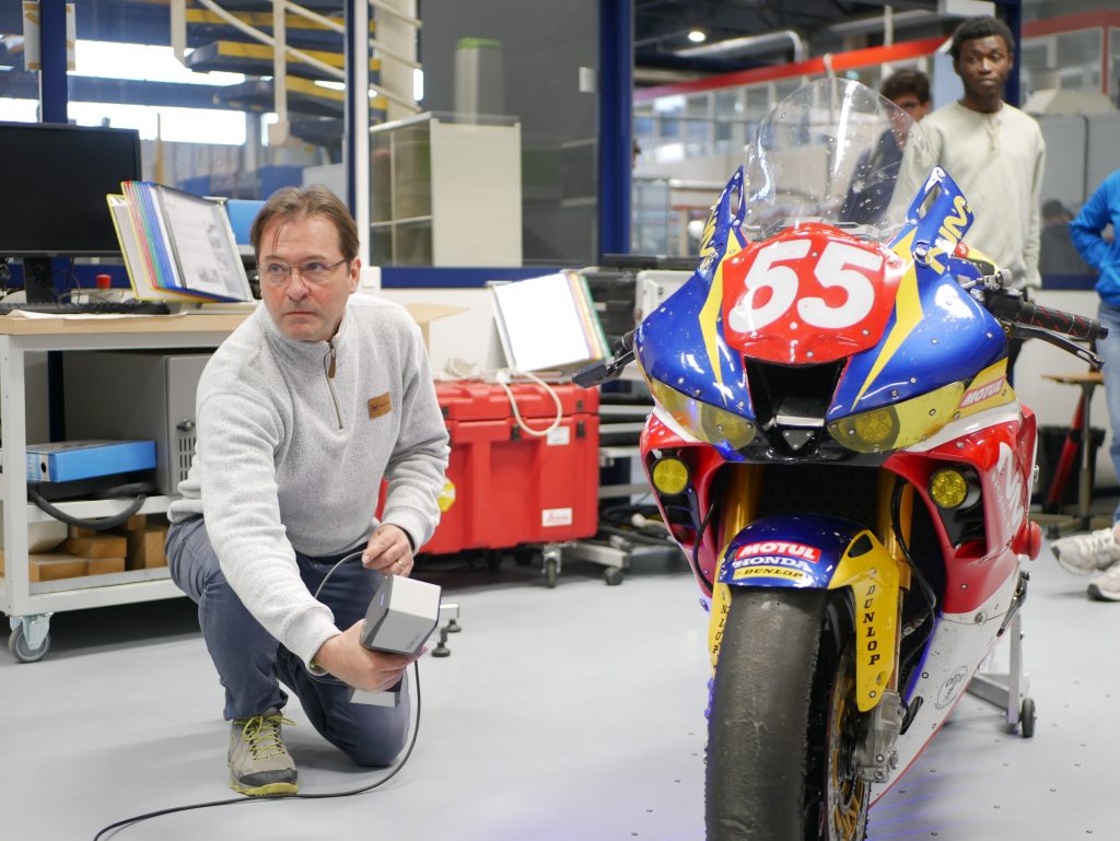 A man using ZEISS T-SCAN hakw 2 to scan an electric motorcycle