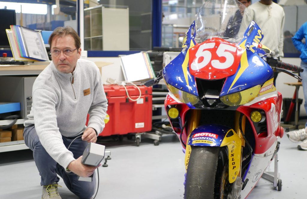 A man using ZEISS T-SCAN hakw 2 to scan an electric motorcycle