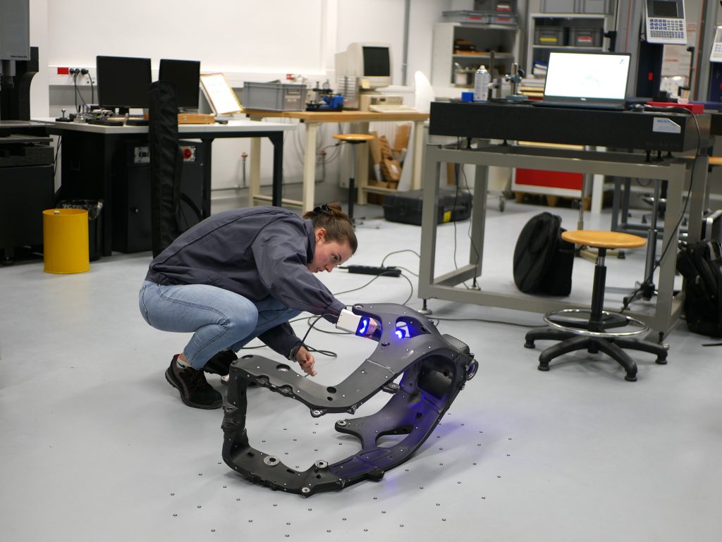 A woman using the hand-held 3D scanner ZEISS T-SCAN hawk 2 to scan a black motorcycle frame